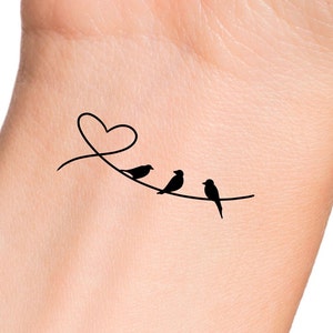 May include: A simple black line drawing tattoo design of three birds perched on a branch with a heart shape above them.