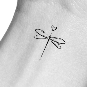 May include: A simple black line drawing of a dragonfly with a small heart above it.