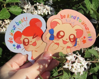 May include: Two colorful stickers featuring cartoon hamsters with encouraging messages. The first sticker says "Do your best!" and features a red-haired hamster with a bright smile. The second sticker says "Be kind to yourself" and features a yellow hamster with a blue bow.