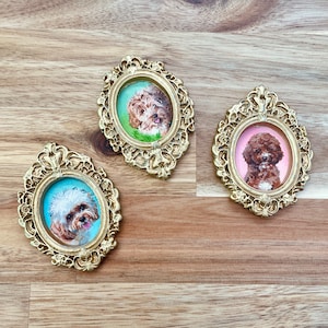 May include: Three ornate gold frames with a decorative design, each containing a painted portrait of a dog. The dogs are brown and white, brown, and brown and white.