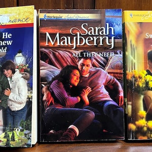 May include: Three paperback books with colorful covers. The books are titled "The Son He Never Knew," "All They Need," and "Sweet Mercy." The covers feature illustrations of people and romantic themes, with the Harlequin Super Romance logo.