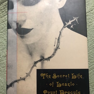 May include: Book cover with a black and white image of a woman's face with a thorny vine around her neck. The title is "The Secret Life of Laszlo Count Dracula" by Roderick Anscombe.
