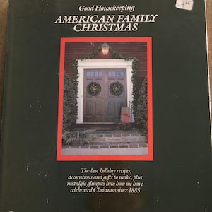 May include: A book cover with a red border featuring a photo of a traditional American home decorated for Christmas. The title of the book is "Good Housekeeping American Family Christmas". The text on the cover reads "The best holiday recipes, decorations and gifts to make, plus nostalgic glimpses into how we have celebrated Christmas since 1885."