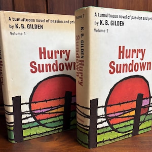 May include: Two vintage books titled "Hurry Sundown" by K.B. Gilden. The covers feature a red sun setting behind a barbed wire fence, with green and yellow grass. Volume 1 and Volume 2 are displayed.