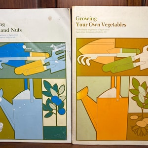 May include: Two vintage book covers with illustrations of gardening tools and watering cans. The book on the left is titled "Growing Fruits and Nuts" and the book on the right is titled "Growing Your Own Vegetables". Both books are from the United States Department of Agriculture.