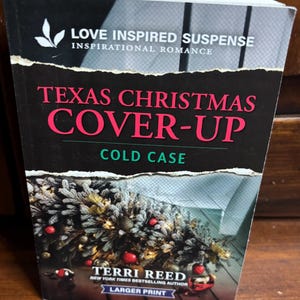 May include: A book cover for "Texas Christmas Cover-Up" by Terri Reed. The cover features a Christmas tree with red ornaments and lights. The title is in large, pink letters against a black background. The book is part of the "Love Inspired Suspense" series.