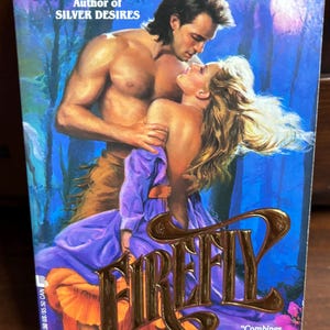 May include: A paperback book cover featuring a romantic scene. The title "FIREFLY" is in gold lettering. The cover art depicts a man and woman embracing, with the author's name "STEFANN HOLM" at the top.