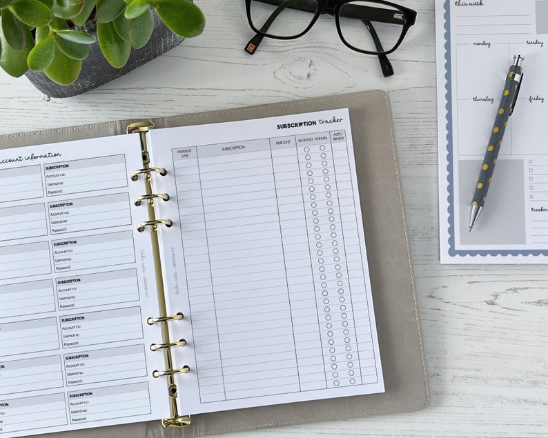 May include: A gray and white subscription tracker with a gold binder. The tracker has sections for account information, subscription details, and a monthly calendar with checkboxes.