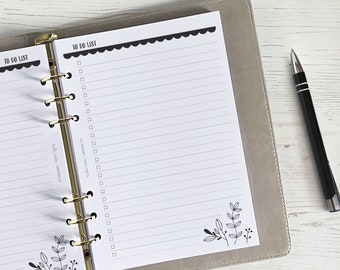 Peut inclure: Un agenda blanc à faire avec un classeur à anneaux doré. L'agenda a un motif floral noir et blanc en bas et une bordure festonnée noire en haut. Le texte "TO DO LIST" est imprimé en haut de la page.