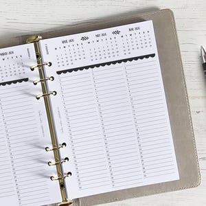 Op de afbeelding: Een grijze planner met gouden ringen en een kalender voor maart, mei en juni 2016. De kalenderpagina's hebben een gegolfde rand en zijn bedrukt met zwarte tekst.