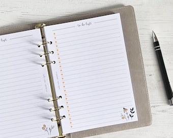 Peut inclure: Une page de liste de choses à faire blanche dans un classeur gris avec des anneaux dorés. La page comporte une section lignée et une section pointillée avec des points orange. La page est décorée d'un simple motif floral noir et orange.
