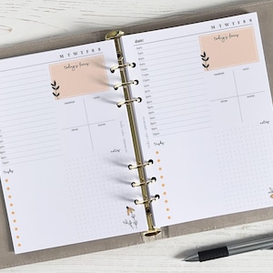 Op de afbeelding: Een witte dagelijkse planner met een gouden binder. De planner heeft een gestippeld rasterpatroon en een sectie voor "de focus van vandaag".