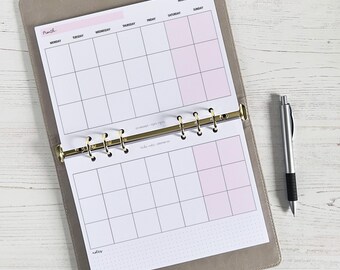 May include: A white monthly planner with a gray cover and gold rings. The planner has a grid layout with days of the week labeled at the top. The month of March is written at the top of the page.