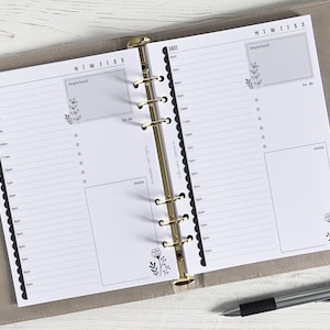 May include: A white daily planner with a gold binder. The planner has a daily schedule, a to-do list, and a notes section. The planner has a floral design.