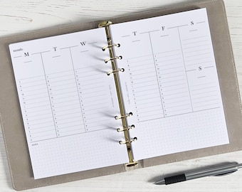 May include: A white weekly planner with a gold binder. The planner has a dotted grid pattern and is divided into seven columns for each day of the week. The days of the week are labeled with the abbreviations M, T, W, T, F, S, and S.