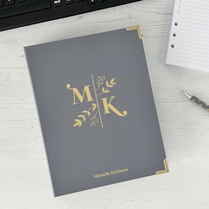 May include: Gray journal with gold accents and a floral design. The initials "MK" are in gold with a gold floral design. The name "Michelle Kirkham" is printed in gold at the bottom.