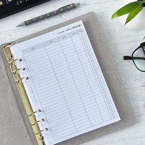 May include: A grey and gold binder with a white page open to a coupon code tracker. The page has columns for store, offer, code, expiry, and used. There are checkboxes next to the used column.