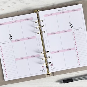 Op de afbeelding: Een wekelijkse maaltijdplanner en boodschappenlijst met roze en witte accenten. De planner heeft secties voor elke dag van de week, met een boodschappenlijst aan de linkerkant.