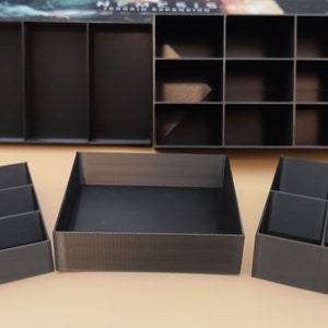 May include: Four black plastic storage boxes with compartments for organising small items. The boxes are different sizes and shapes, and they are all empty.