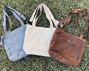 Puede incluir: Tres bolsos tote de pana en diferentes colores: gris, beige y marrón. Cada bolso tiene un bolsillo único en la parte delantera y correas ajustables.