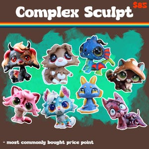 May include: A collection of eight stylized animal figurines with large eyes, including a black and red horned creature, a brown dog, a blue dragon, a mushroom-capped animal, a pink cat, a multi-colored creature, a blue alien, and a red monster.