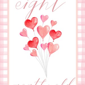 May include: A pink and white gingham background with a white card in the center. The card has the text "eight months old" written in pink cursive. There are eight pink and red heart-shaped balloons in the center of the card.