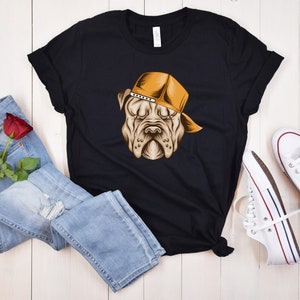 May include: Black t-shirt with a graphic of a dog wearing a yellow baseball cap. The dog has a serious expression.