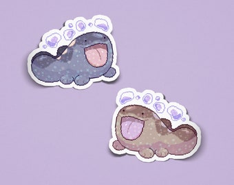 May include: Two pixel art stickers featuring a creature with a wide open mouth and tongue sticking out. One sticker is dark blue with light blue sparkles, and the other is brown with light brown sparkles. Both have purple bubbles above them.