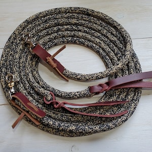 May include: A black and tan braided rope halter with brown leather straps and silver snap hooks.