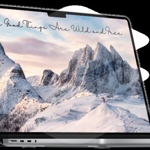 Könnte beinhalten: Ein silberner Laptop mit einem weißen Hintergrundbild von schneebedeckten Bergen. Der Text "All Good Things Are Wild and Free" ist in schwarzer Kursivschrift auf dem Bildschirm geschrieben.
