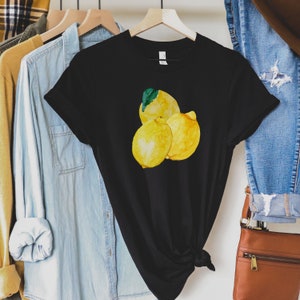 K&ouml;nnte beinhalten: Schwarzes T-Shirt mit einer Aquarell-Illustration von drei Zitronen. Die Zitronen sind gelb mit gr&uuml;nen Bl&auml;ttern.