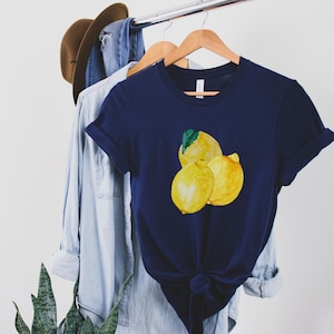 K&ouml;nnte beinhalten: Ein marineblaues T-Shirt mit einer Aquarell-Illustration von drei Zitronen auf der Vorderseite.