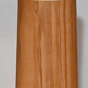 May include: A wooden container with a light brown finish and a thin, light brown band around the middle. The container has a cylindrical shape and a smooth, polished surface.