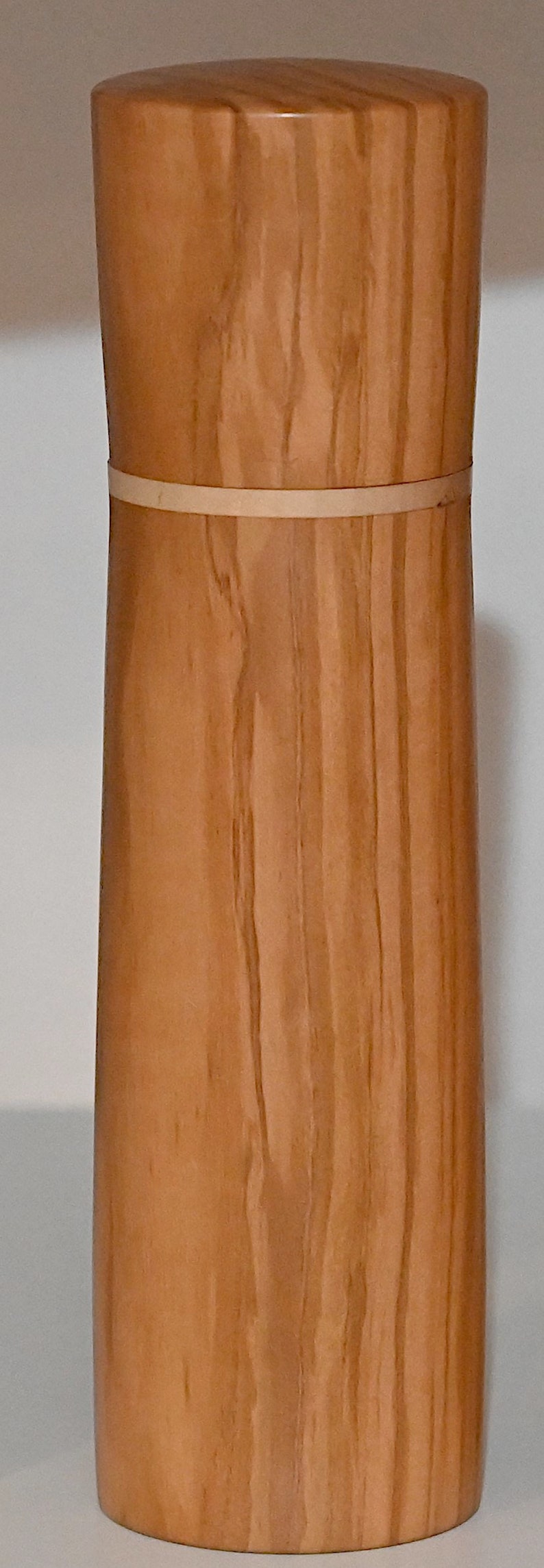 May include: A wooden container with a light brown finish and a thin, light brown band around the middle. The container has a cylindrical shape and a smooth, polished surface.