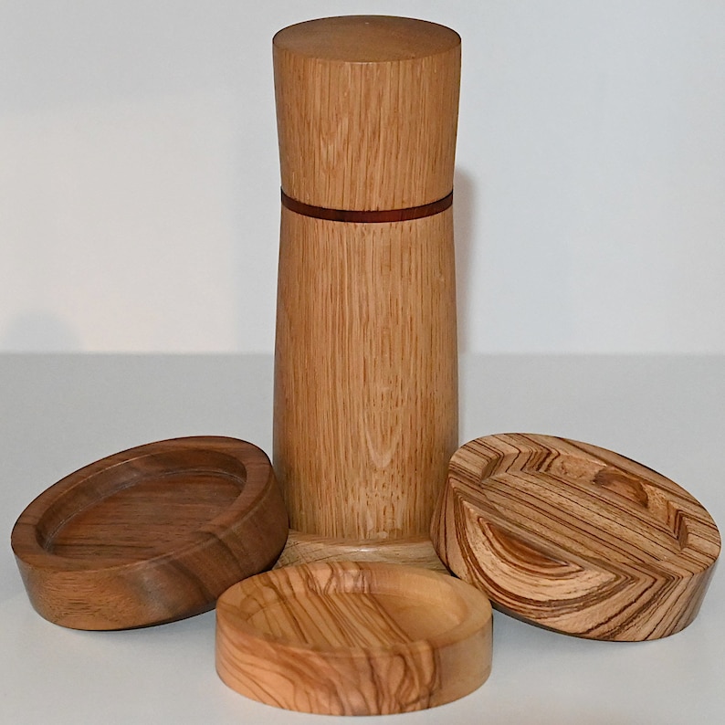 May include: A set of three wooden containers with a natural wood grain finish. The containers are cylindrical in shape and have a red accent band around the middle. The containers are made of wood and have a natural wood grain finish.