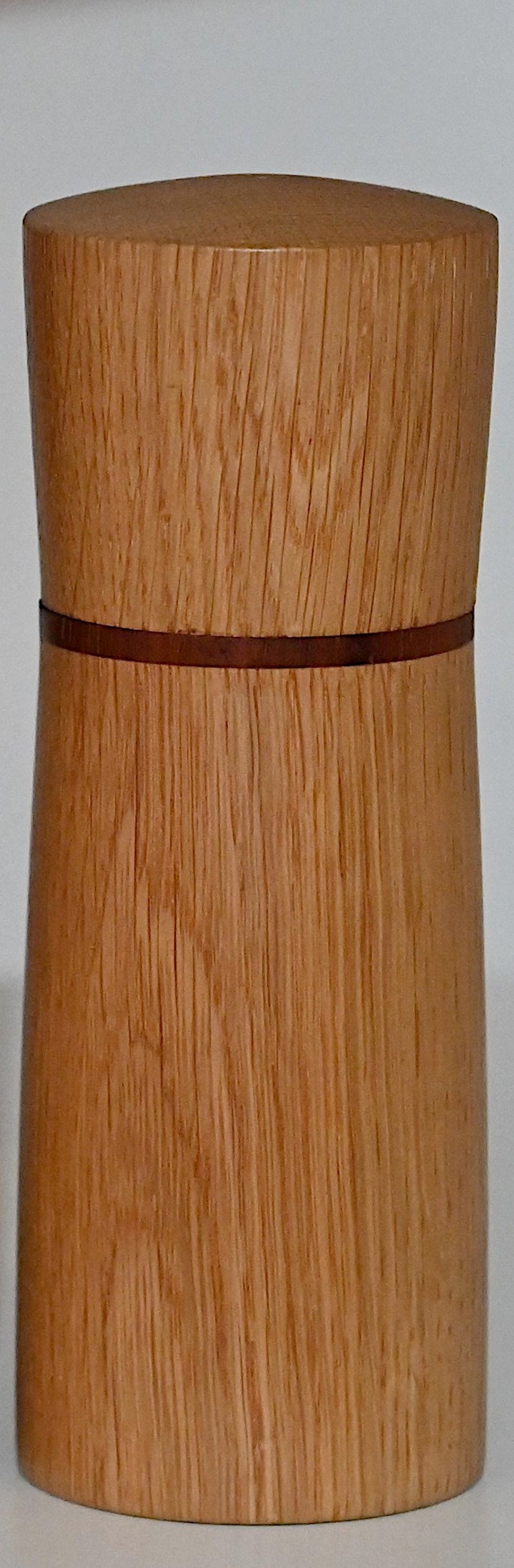 May include: A wooden container with a brown wood grain pattern and a thin brown band around the middle.