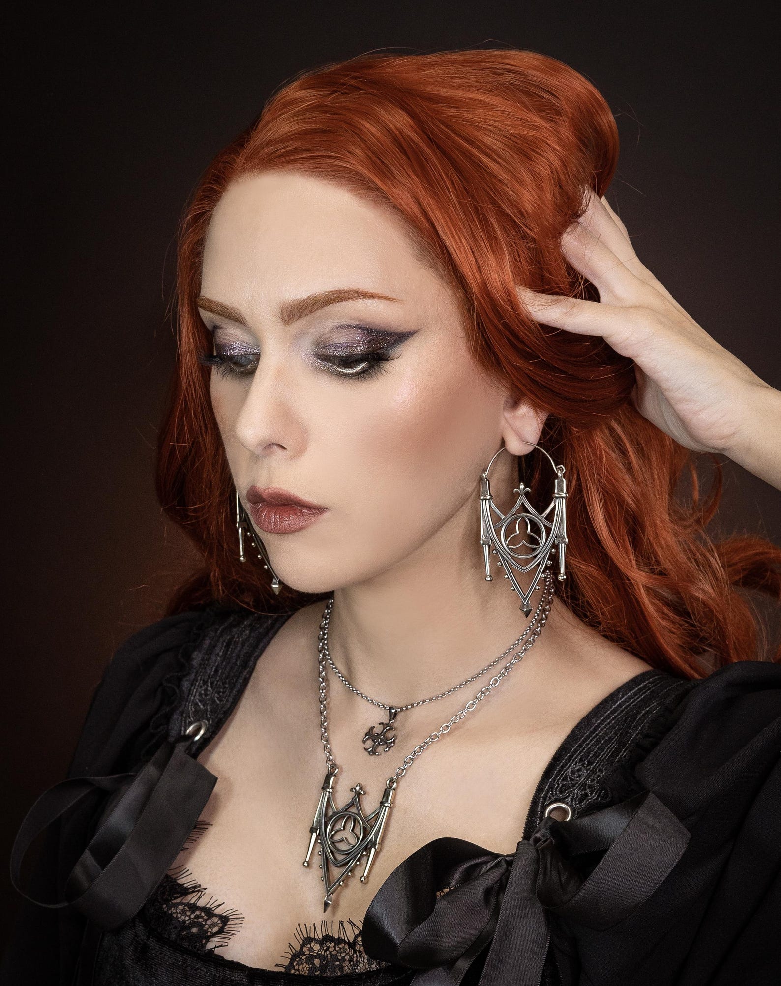 Model wearing large silver cathedral earrings with matching gothic necklace