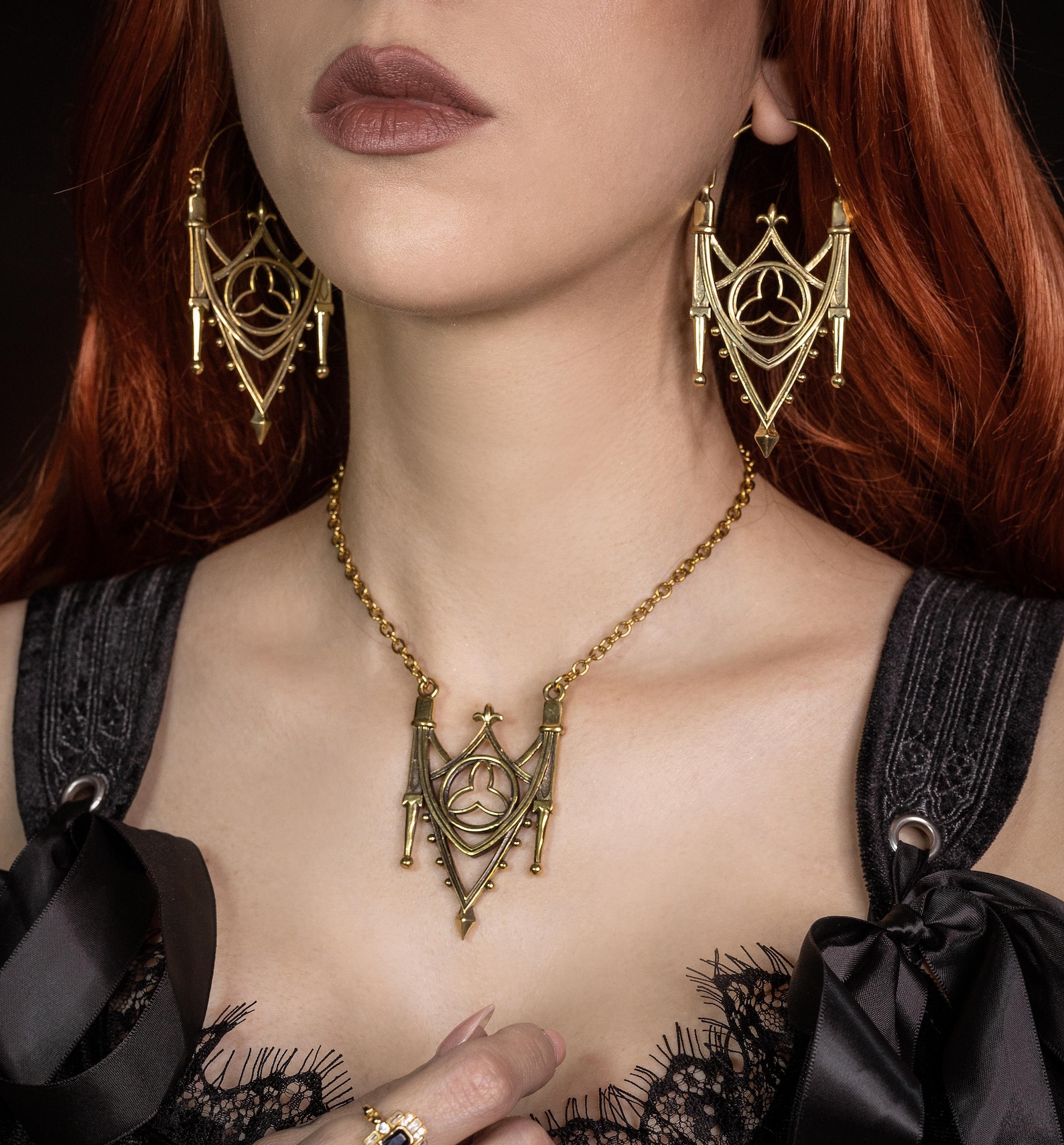 Gold cathedral-style hoop earrings and necklace on model in black lace dress