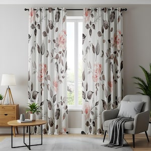 May include: A pair of floor-length curtains featuring a white background with a watercolour-style pattern of soft peach roses and dark grey leaves. The curtains are hung on a black rod with silver grommets, displaying a repeating floral design.