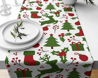 May include: White table runner with a repeating pattern of Christmas trees, reindeer, holly, ornaments, and stockings in red and green.