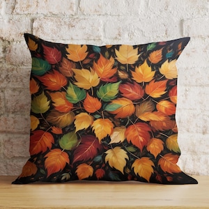 May include: A throw pillow featuring a black background with a pattern of colourful autumn leaves in shades of red, orange, yellow, and green.