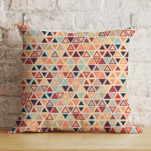 Puede incluir: Una almohada decorativa con un patrón geométrico de triángulos naranja, rojo, amarillo, azul y verde.