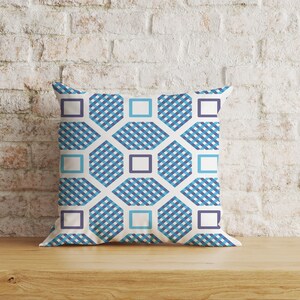 May include: A white cushion with a geometric pattern in shades of blue. The pattern features a series of hexagons and squares.