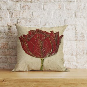 May include: A decorative cushion featuring a red and gold tulip design on a cream background.