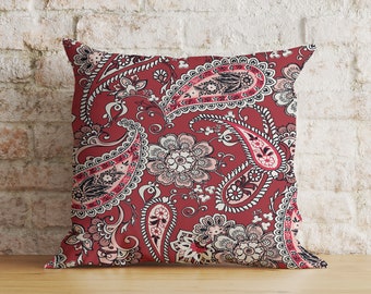 Puede incluir: Cojín rojo con un patrón de paisley en tonos de rosa y blanco.
