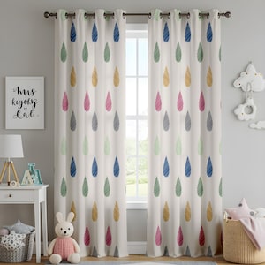 May include: Cream-coloured eyelet curtains featuring a pattern of colourful, stylised raindrops in blue, green, yellow, pink, and grey. The curtains hang in front of a window, with a framed print and decorative items visible.