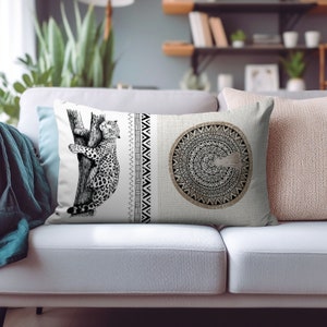 Puede incluir: Una almohada blanca con una ilustración en blanco y negro de un jaguar trepando a un árbol en un lado y un diseño de mandala en blanco y negro en el otro.