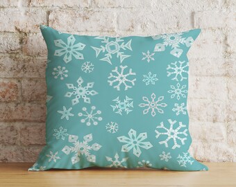 May include: A teal blue throw pillow with a white snowflake pattern.