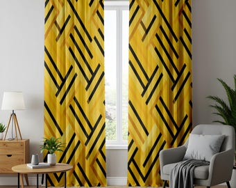 Pode incluir: Um par de cortinas do chão ao teto com um padrão geométrico de linhas pretas arrojadas sobrepostas a vários tons de amarelo e dourado. As cortinas estão penduradas numa barra preta com ilhós, exibindo um design angular repetitivo no tecido.