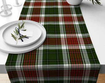 May include: A green, red, and white plaid table runner with a white background. The runner is made of a woven fabric and has a subtle sheen.